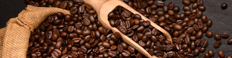 Variety of cups of coffee and coffee beans in burlap sack on black background